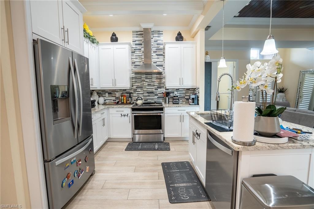 Modern kitchen featuring white cabinetry, stainless steel appliances, light granite countertops, a mosaic tile backsplash, and light wood-finish flooring