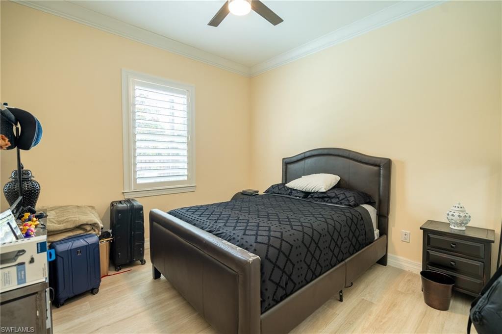 Bedroom featuring a ceiling fan, crown molding, and light-toned wood-finish flooring