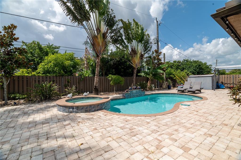Outdoor living area featuring a freeform swimming pool with integrated spa and waterfall feature, surrounded by paver patio decking