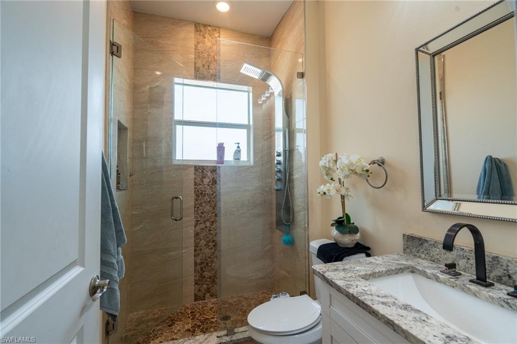 Spacious bathroom featuring a glass-enclosed shower with stone tile, mosaic accent strip, and a built-in shower niche
