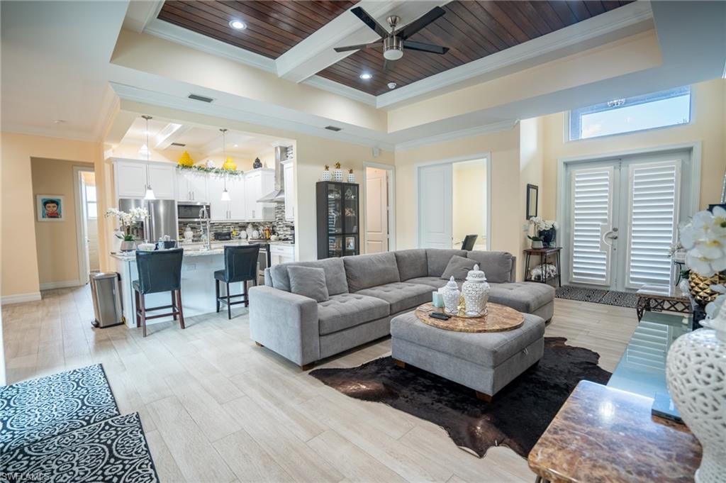 Open-concept living area featuring light wood-finish flooring, a coffered ceiling with wood paneling and recessed lighting, and a contemporary ceiling fan