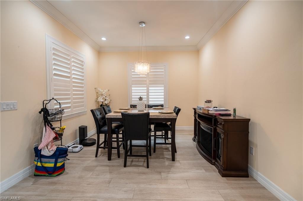 Dining area featuring light wood-finish flooring, white crown molding, and recessed lighting