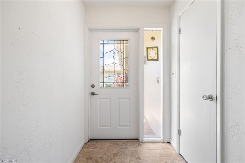 Entryway featuring a white paneled door with decorative glass inserts, a full-length sidelight, and textured white walls