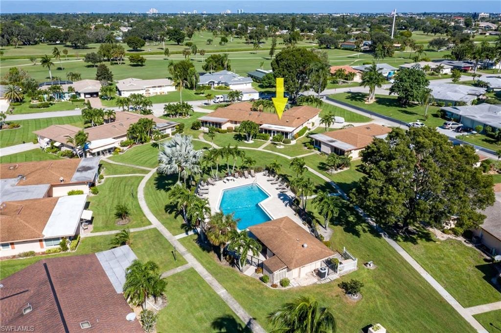 Aerial view showcasing the property with a brown shingle roof, surrounded by green lawns and mature landscaping
