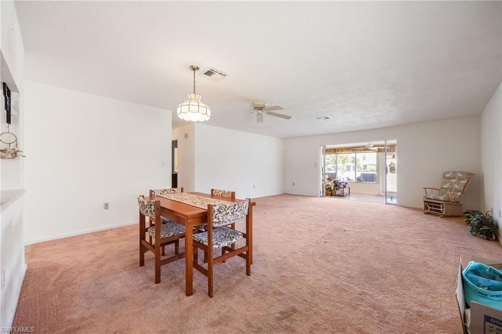 Open-concept living area featuring light-colored walls and a built-in ceiling fan