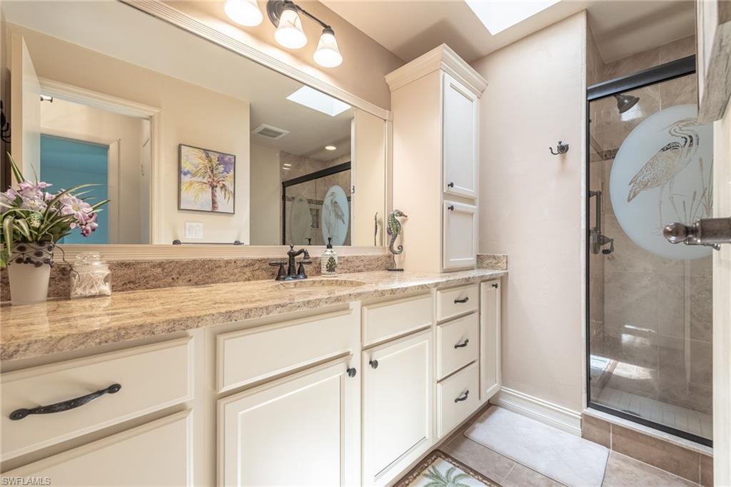 Bathroom vanity featuring a granite countertop, dual sinks, and white shaker-style cabinetry