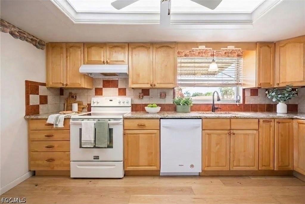 Kitchen featuring virtual flooring, wood cabinetry, granite-style countertops, and a checkered tile backsplash