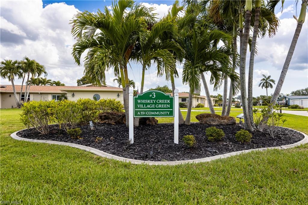 Landscaped entrance featuring mature palm trees and lush shrubs