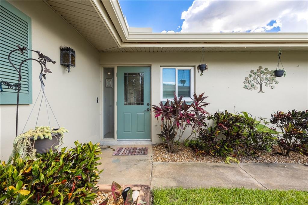 Exterior featuring a teal entry door with decorative glass, stucco finish, and a window with white framing