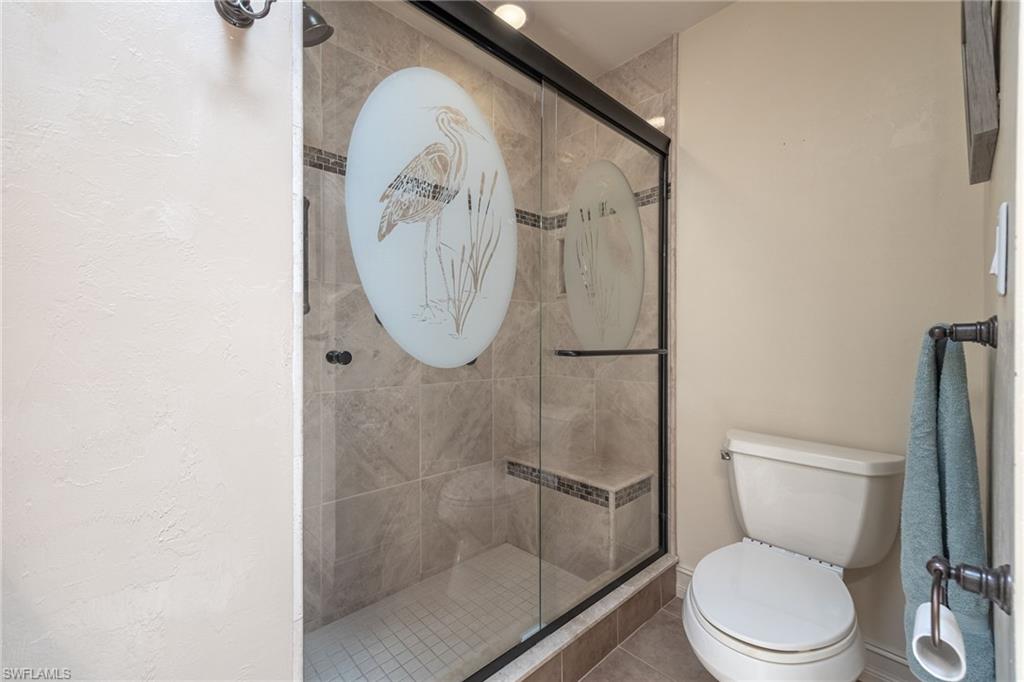 Framed glass shower enclosure featuring an etched design and tiled interior
