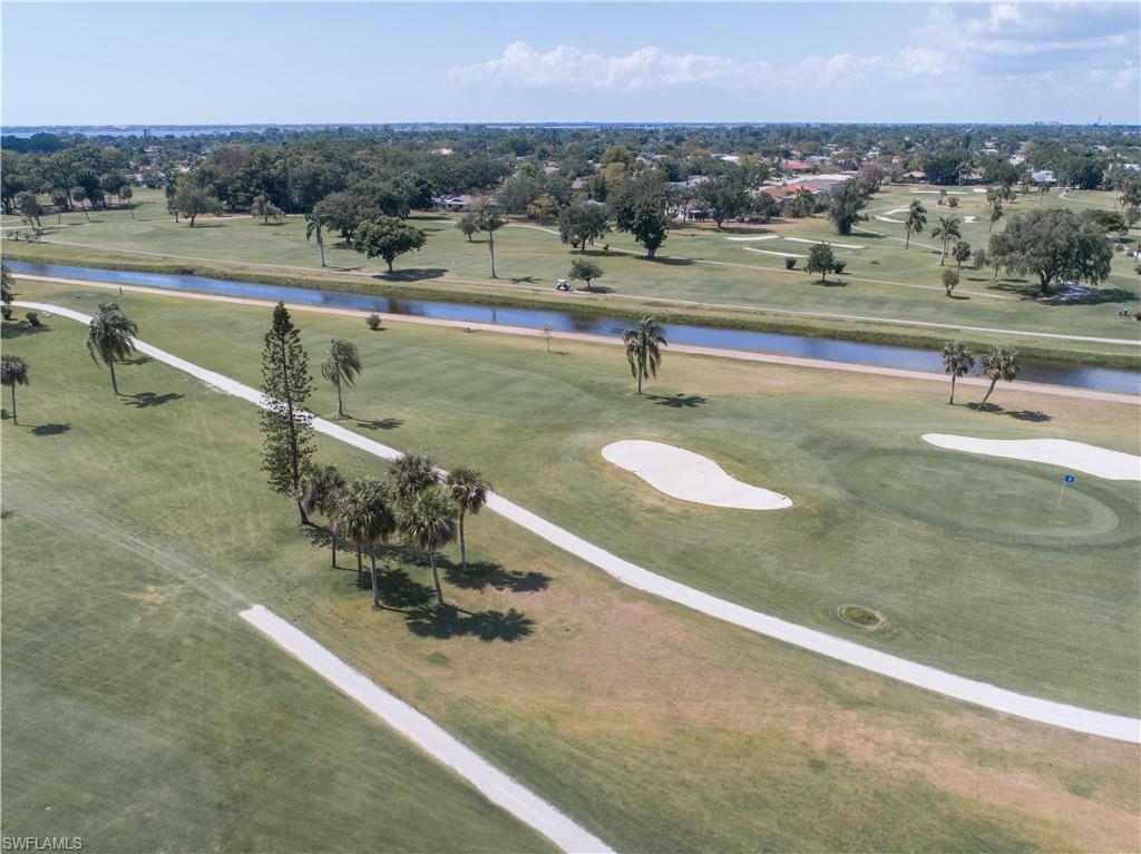 Expansive green with sand traps, a putting green with a flag, and cart paths
