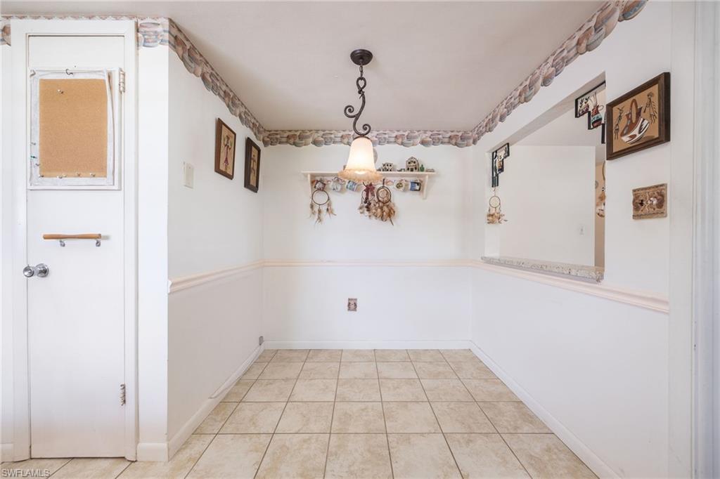 Neutral-toned ceramic tile flooring complements the white walls and decorative chair rail molding