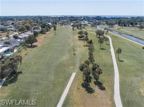 Expansive golf course fairway featuring manicured greens, scattered palm trees, and a concrete cart path