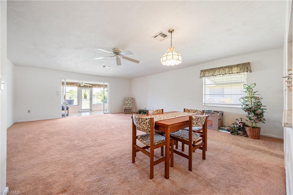 Expansive living area featuring carpet flooring, a ceiling fan, and a chandelier