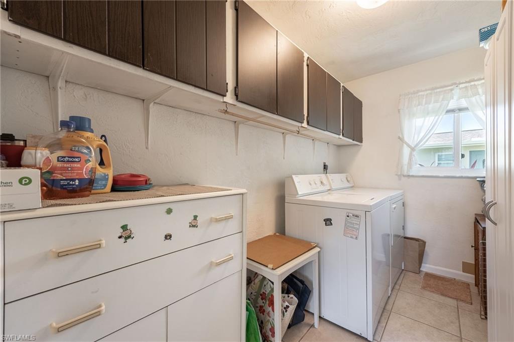 Utility room featuring tiled flooring and upper dark wood-finish cabinetry