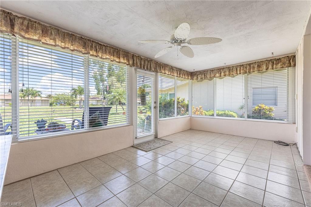 Enclosed sunroom featuring a ceiling fan, light-toned tile flooring, and multiple windows with blinds