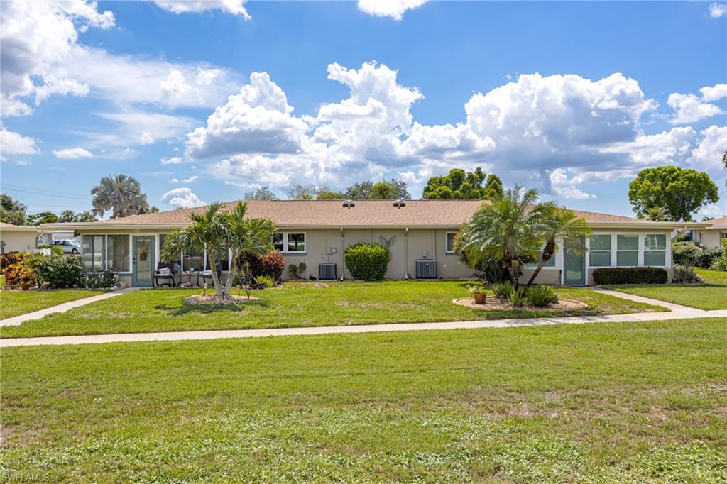 Single-story residence featuring a neutral exterior, a tan roof, and a lush green lawn