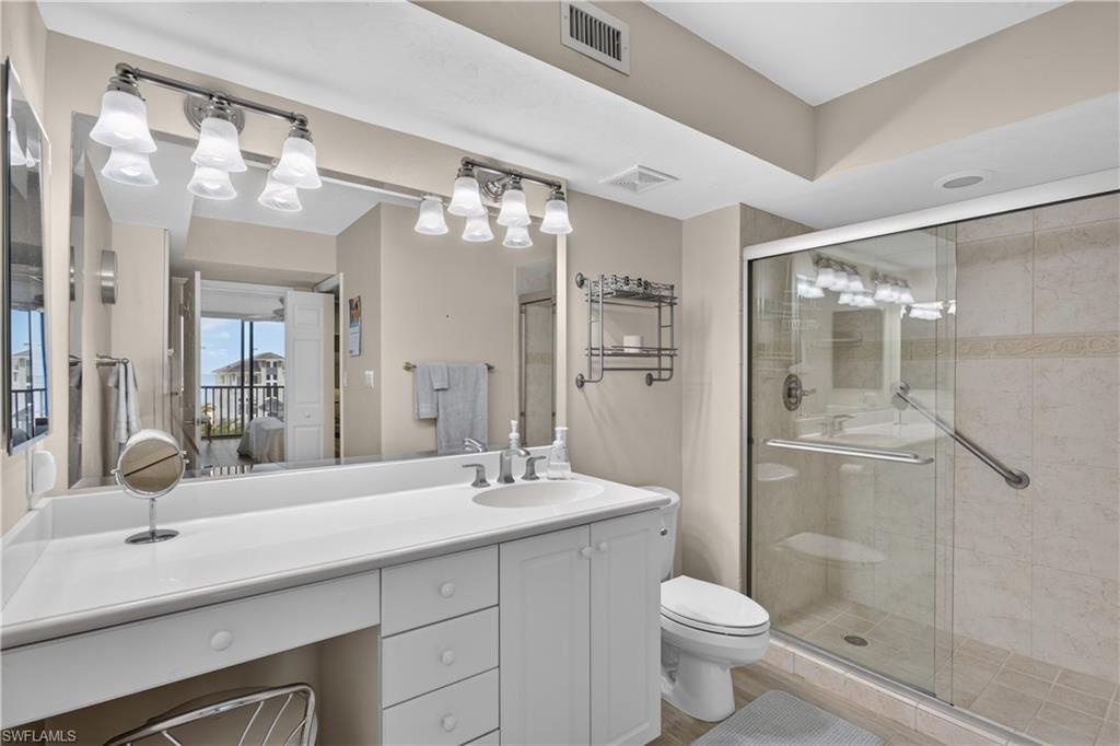 Vanity, tiled shower, heavy glass shower doors.