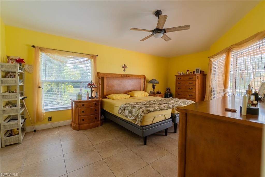 Bedroom with light tile patterned floors, baseboards, and ceiling fan
