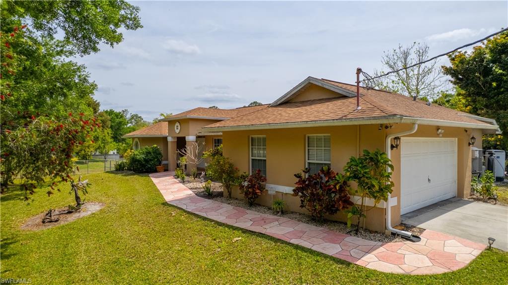 View of front of home featuring driveway, fence, an attached garage, a front lawn, and stucco siding