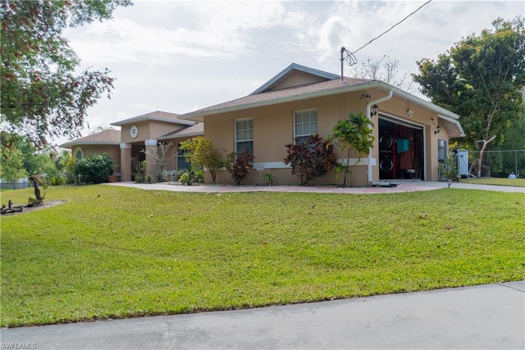 View of front of home with stucco siding, a front lawn, and an attached garage