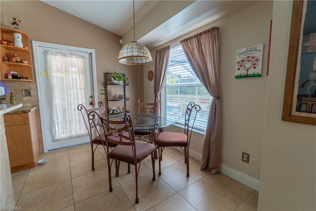 Dining space featuring light tile patterned flooring, baseboards, and lofted ceiling