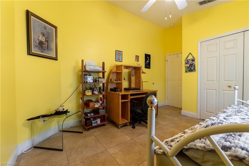 Bedroom with baseboards, light tile patterned flooring, visible vents, a ceiling fan, and a closet