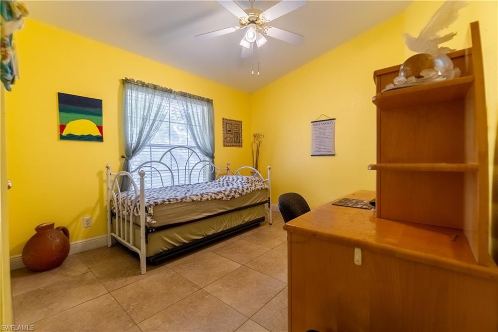 Bedroom with baseboards, lofted ceiling, ceiling fan, and light tile patterned floors