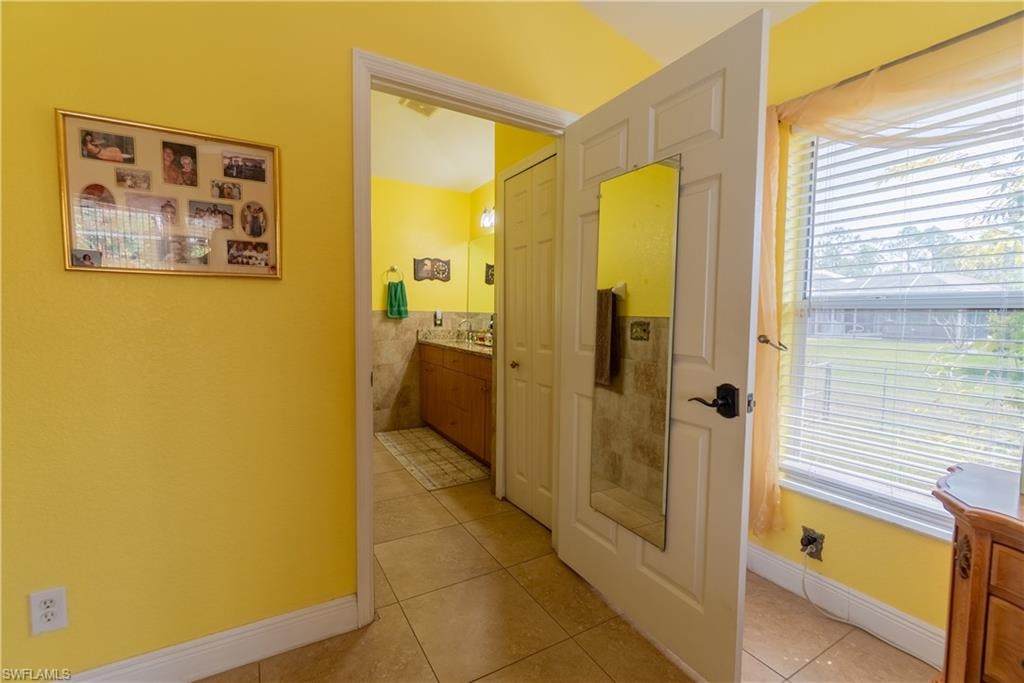 Corridor with baseboards, light tile patterned floors, and plenty of natural light