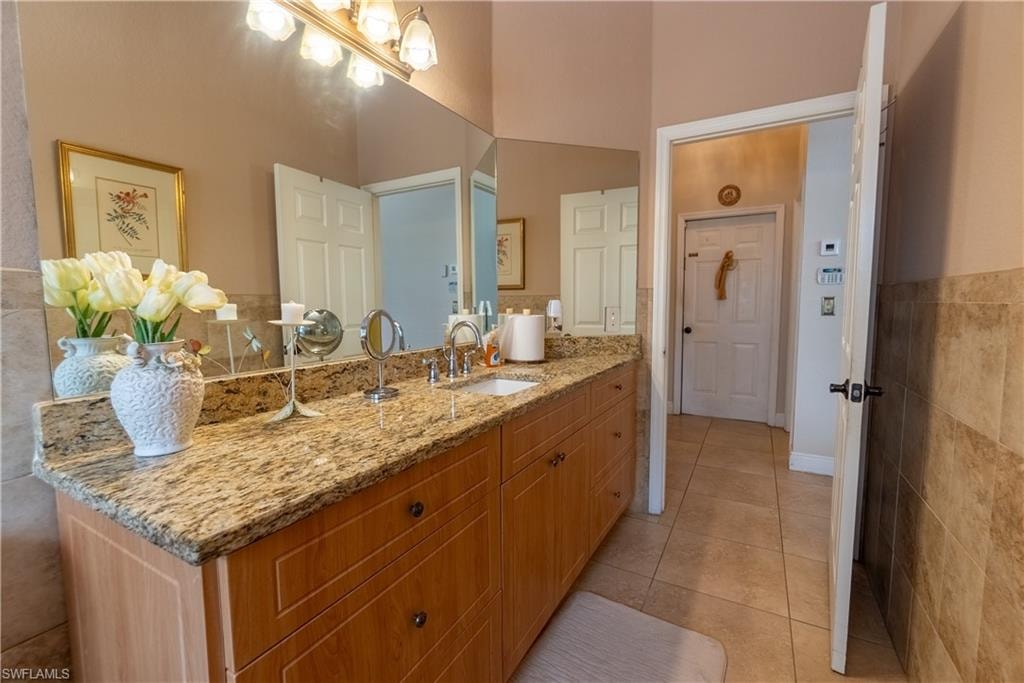 Bathroom with tile walls, tile patterned floors, and vanity