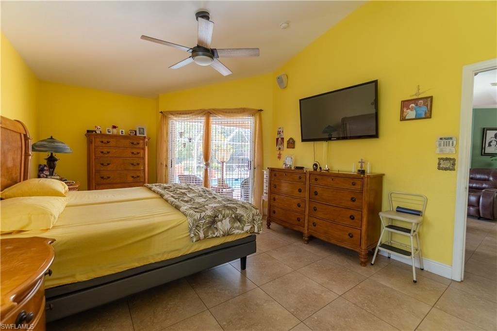 Bedroom with tile patterned floors, ceiling fan, baseboards, and access to outside