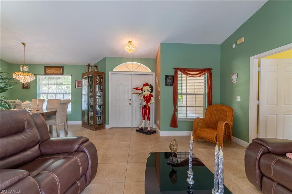 Living room with light tile patterned floors, baseboards, and a chandelier