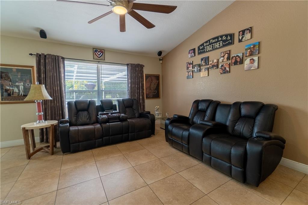 Living area featuring light tile patterned flooring, baseboards, vaulted ceiling, and ceiling fan