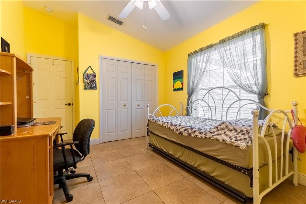 Bedroom featuring light tile patterned flooring, a closet, a ceiling fan, lofted ceiling, and visible vents