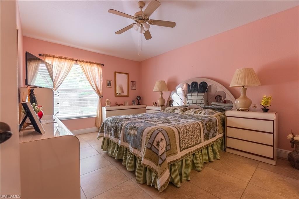 Bedroom with a ceiling fan, light tile patterned floors, and baseboards