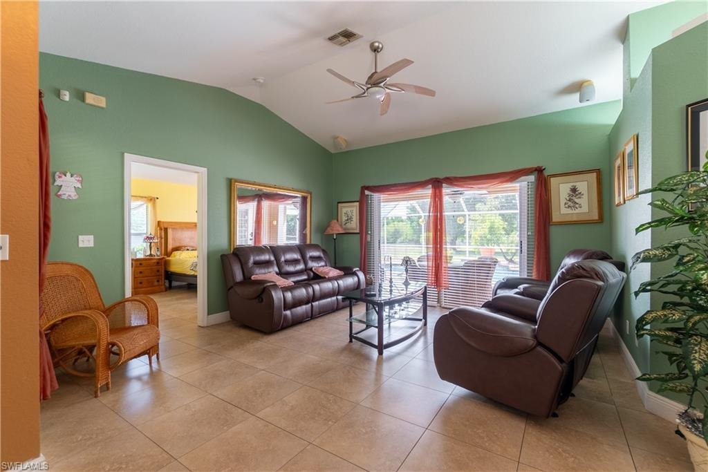 Living room with light tile patterned flooring, visible vents, baseboards, a ceiling fan, and vaulted ceiling