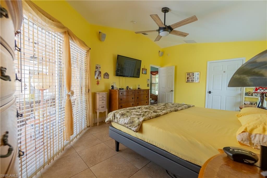 Bedroom with light tile patterned floors, vaulted ceiling, and ceiling fan