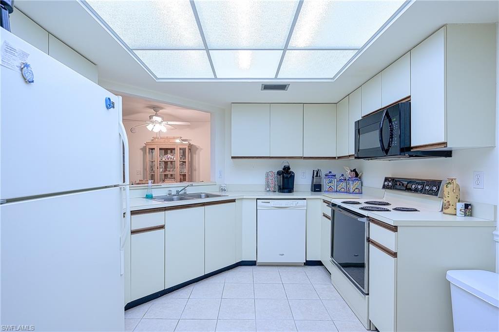 Kitchen featuring white appliances, sink, ceiling fan, and white cabinets