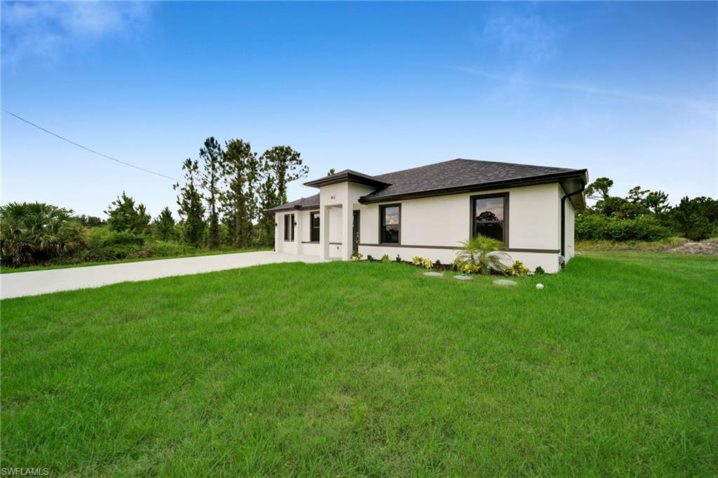 Contemporary single-story residence featuring a light-colored stucco exterior with dark trim windows, a dark shingle roof, and a concrete driveway