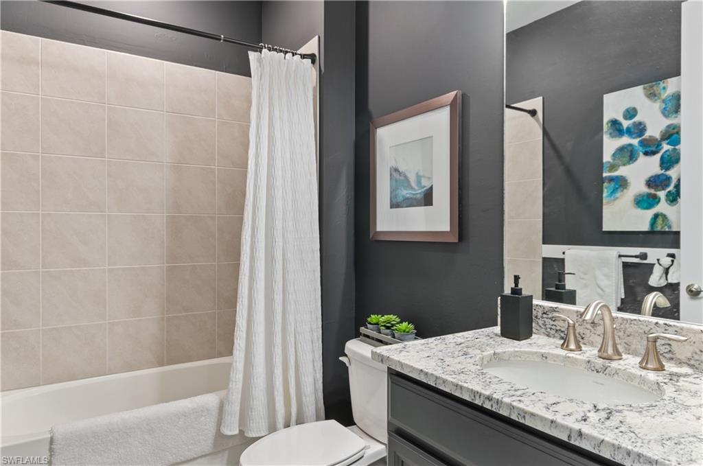 Bathroom featuring a single vanity with a granite-style countertop, undermount sink, and brushed nickel fixtures