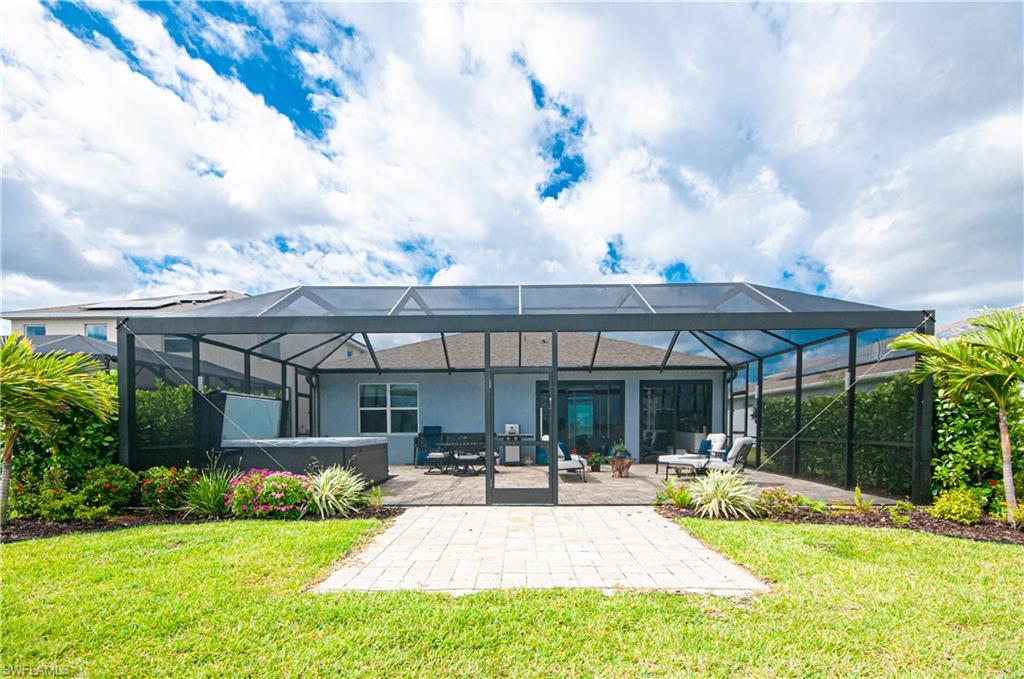 Expansive screened enclosure featuring a hot tub and paver patio