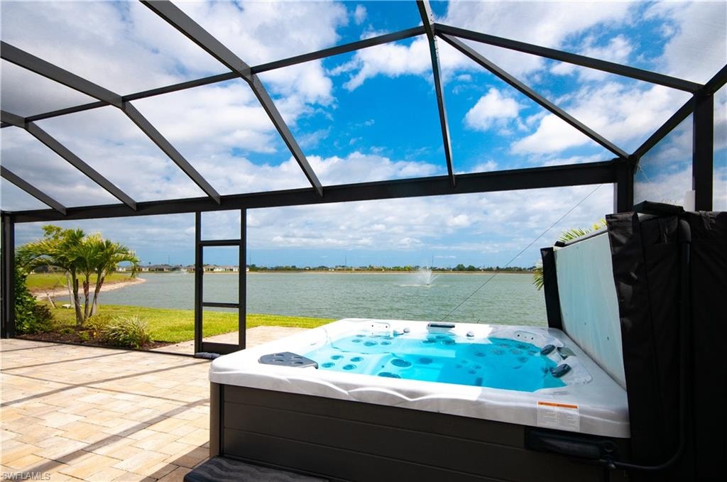Screened patio featuring a built-in spa, paver flooring, and panoramic water views