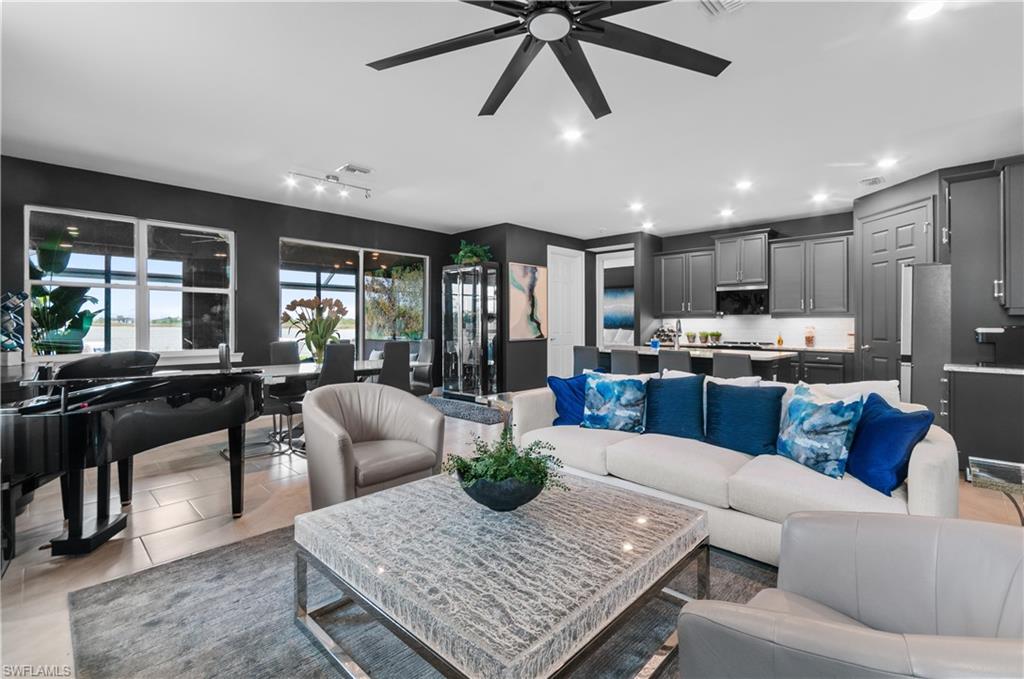 Open-concept living space featuring a modern kitchen with dark cabinetry and white countertops, a dining area with expansive windows, and light wood-finish flooring