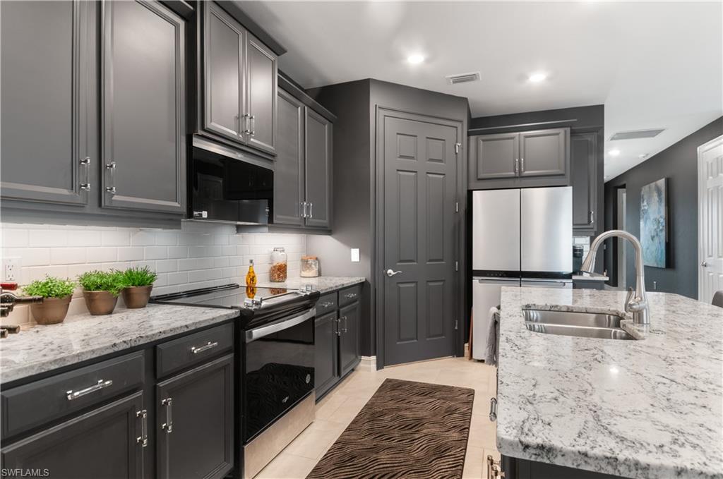 Kitchen featuring gray cabinetry, white subway tile backsplash, stainless steel appliances, and light-toned countertops