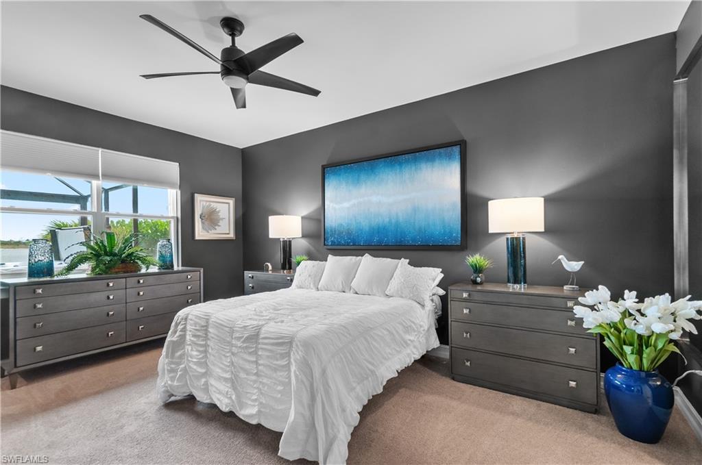 Spacious room featuring neutral carpeting, dark accent walls, a large window, and a ceiling fan with integrated lighting