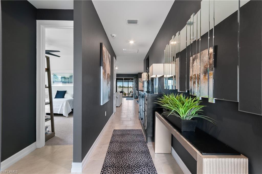 Hallway featuring dark gray walls, light-toned tile flooring, and white baseboards