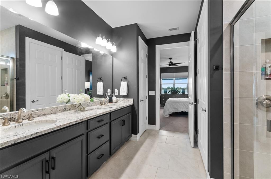 Bathroom featuring a dual vanity with undermount sinks, stone-finish countertop, dark wood-finish cabinetry, and brushed nickel fixtures