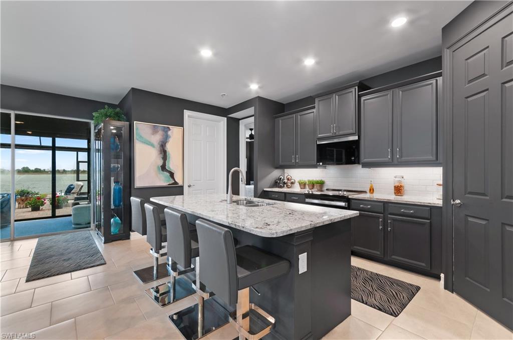 Kitchen featuring an oversized island with a stone countertop, dark cabinetry, and integrated appliances