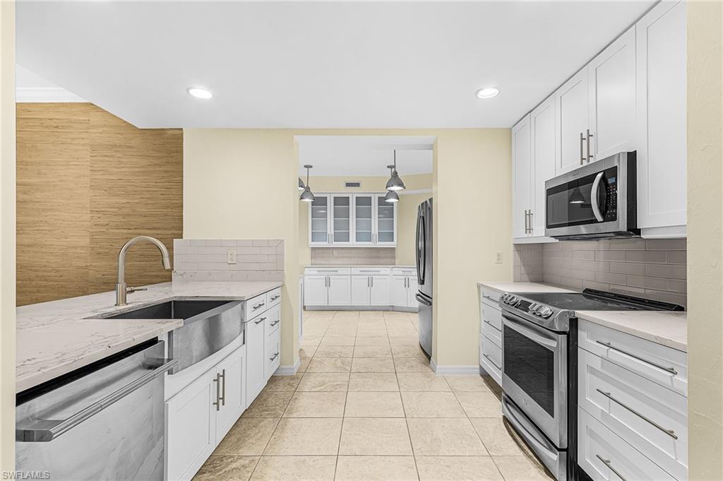 Kitchen featuring white shaker cabinetry, stainless steel appliances, light-toned countertops, and tile flooring