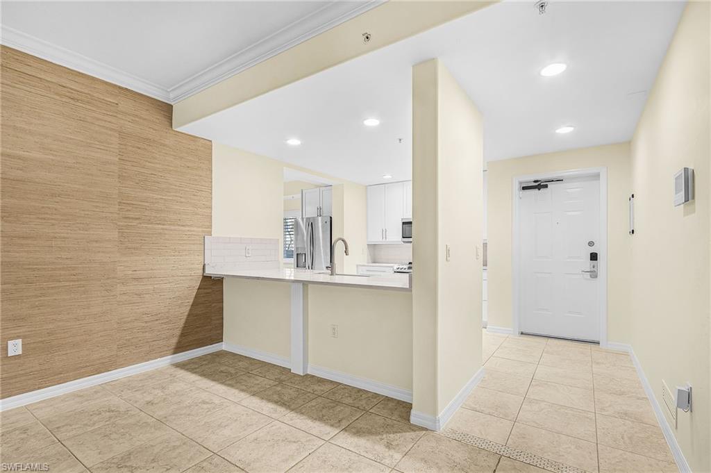 Open-concept living space featuring a breakfast bar, recessed lighting, tile flooring, and a decorative wall covering